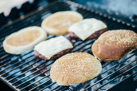 selective focus of delicious fresh burgers ingredients grilling on barbecue gridの写真素材