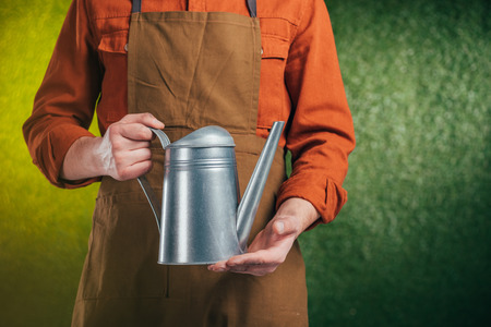 partial view of man holding watering can on blurred background, earth day conceptの写真素材