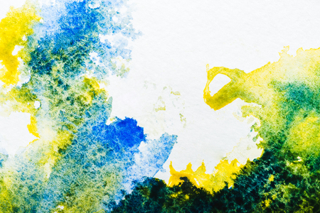 top view of blue and yellow watercolor spills on white paperの写真素材