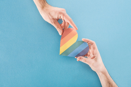 cropped view of men holding rainbow colored paper heart on blue background, lgbt conceptの写真素材