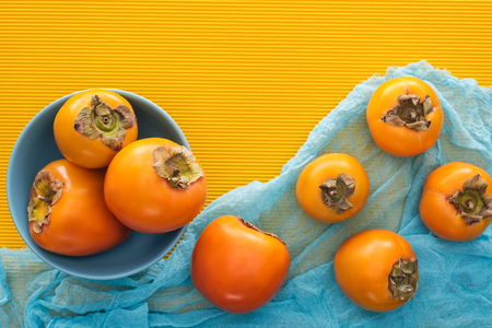top view of whole orange persimmons on blue plate and clothの写真素材