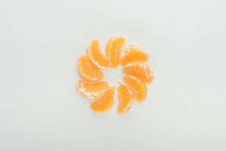 flat lay with peeled tangerine slices arranged in circle on white backgroundの写真素材