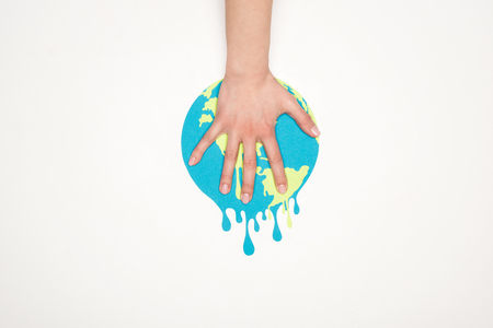 cropped view of female hand on paper cut melting globe on white background, global warming conceptの写真素材