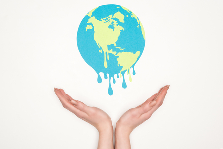 cropped view of woman holding open hands under paper cut melting globe on white background, global...