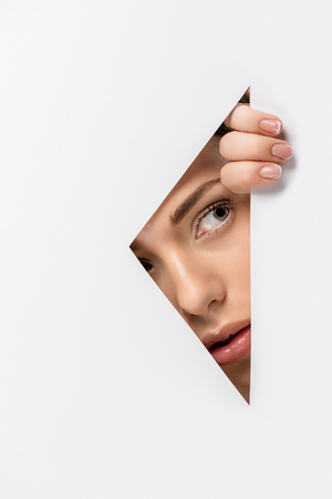 young woman looking away through hole on whiteの写真素材