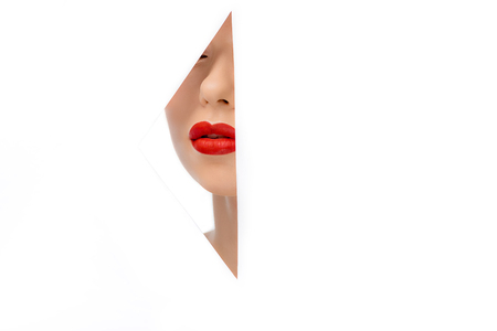 beautiful young woman with red lips, view through hole on whiteの写真素材