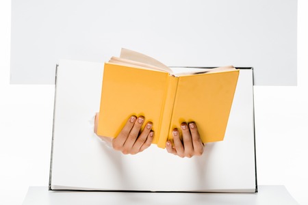 cropped shot of woman holding book through holes on whiteの写真素材