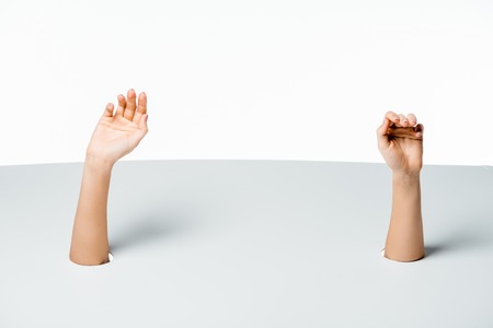 cropped shot of female hands through holes on white backgroundの写真素材