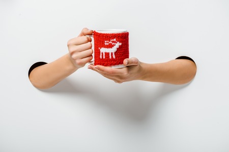 cropped image of woman holding cup of coffee decorated with deer through holes on whiteの写真素材