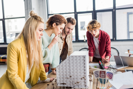 concentrated group of female and male architects working together on house model in loft officeの写真素材