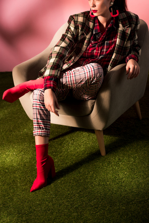 cropped view of stylish woman in checkered suit posing in armchairの写真素材