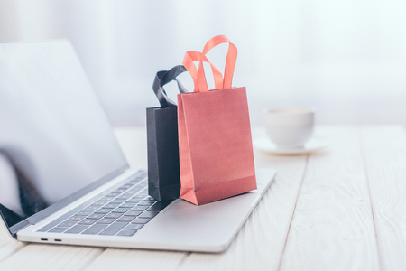 selective focus of small shopping bags on laptop with cup on backgroundの写真素材