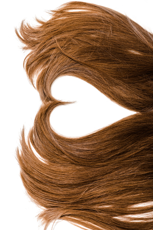 cropped view of long brown female hair in shape of heart isolated on whiteの写真素材