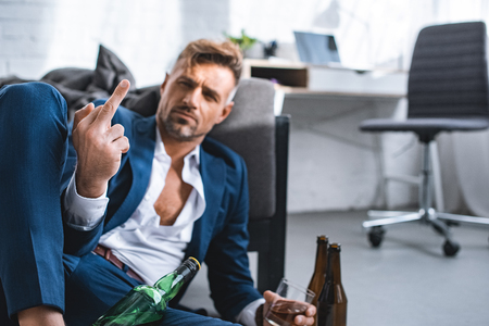 selective focus of middle finger of drunk businessman in living roomの写真素材