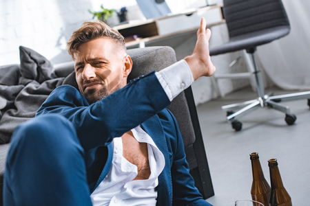 drunk businessman putting hand against sunshine in living roomの写真素材