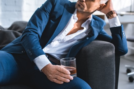 cropped view of businessman holding glass with alcohol drinkの写真素材