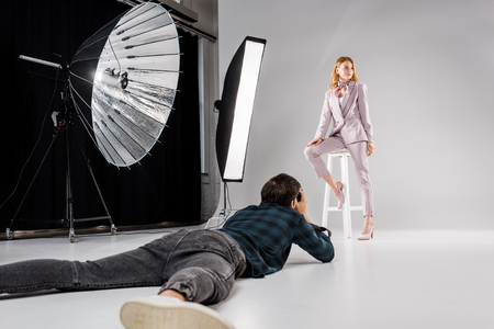 photographer lying and shooting beautiful female model in photo studioの写真素材
