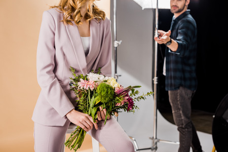 cropped shot of photographer and young female model with bouquet of flowers in photo studioの写真素材