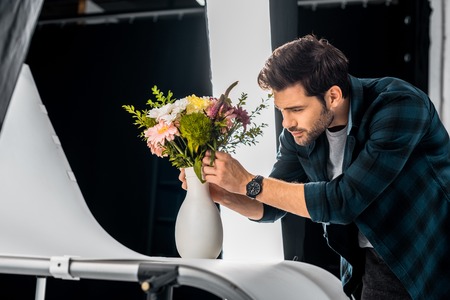 handsome young photographer arranging flowers in photo studioの写真素材