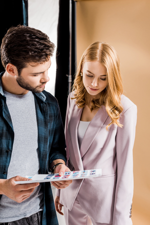 photographer and young woman looking at pictures in photo studioの写真素材