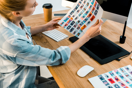cropped shot of young retoucher holding photos at workplaceの写真素材
