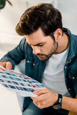 handsome young photographer looking at pictures in officeの写真素材