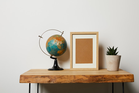 globe near frame and plant in pot on wooden table