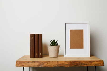 books near cactus in pot and frame on wooden tableの写真素材