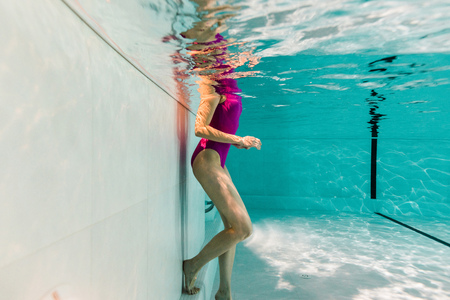 cropped view of woman underwater in swimsuit in blue waterの写真素材