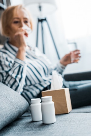 selective focus of tissue box and bottles of medicine with senior woman on backgroundの写真素材