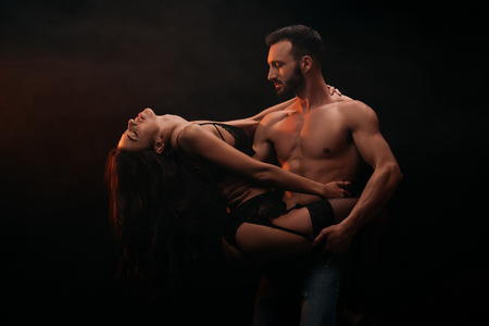 attractive passionate couple hugging isolated on blackの写真素材