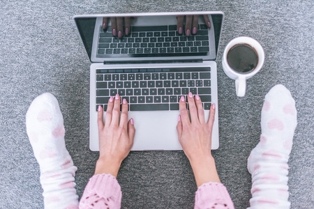 top view of female blogger typing on laptop keyboard near cup of coffeeの写真素材