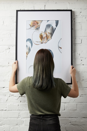 back view of woman holding drawing in black square frame in handsの写真素材