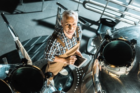 overhead view of handsome male brewer using digital tablet in brewery