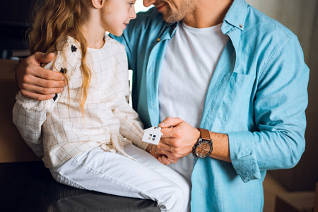 cropped view of cute kid looking at father holding house shaped key chianの写真素材