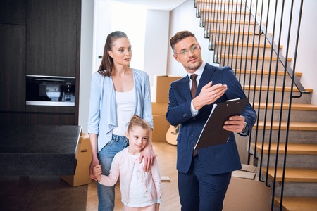 handsome broker showing something to attractive woman standing with daughterの写真素材