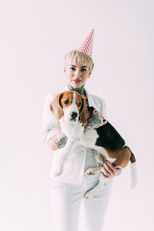 blonde woman with tattoos holding in arms cute beagle dog isolated on greyの写真素材