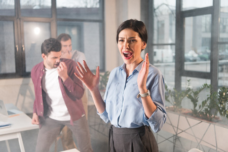 scared businesswoman standing yelling near coworkers in office with smokeの写真素材