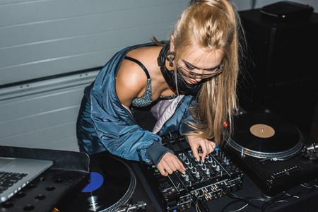 focused dj woman touching dj mixer and standing near vinyl recordsの写真素材