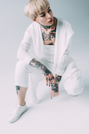 attractive woman with tattoos sitting on grey backgroundの写真素材