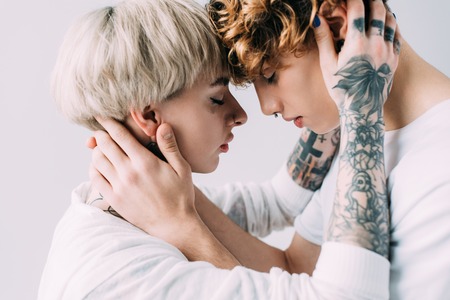 girlfriend embracing boyfriend with curly hair isolated on greyの写真素材