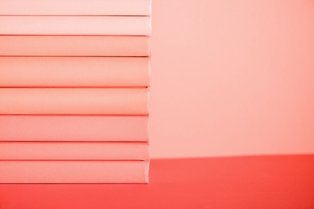 stack of books on living coral background. Color of the year 2019 concept