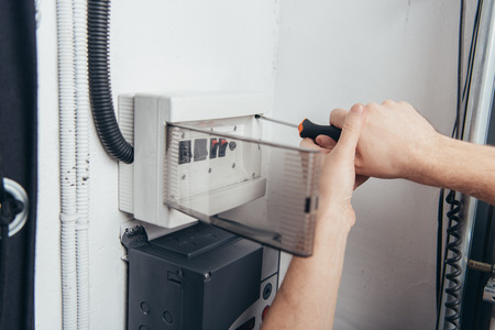 cropped image of male electrician repairing electrical box by screwdriverの写真素材
