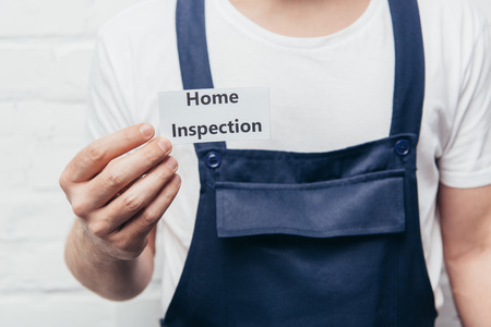 cropped image of male craftsman showing card with lettering home inspection