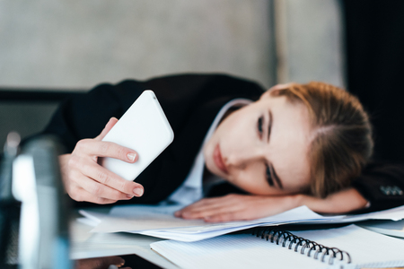 selective focus of smartphone in hand of businesswoman at work-tableの写真素材