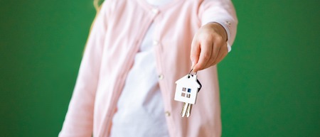 cropped view of kid holding house shaped key chain isolated on green