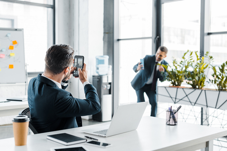 selective focus of businessman talking photo of coworker in modern officeの写真素材