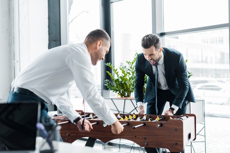 happy businessmen playing table football in modern officeの写真素材