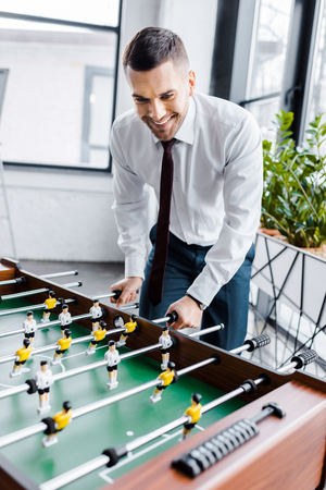 handsome businessman in formal wear playing table footballの写真素材