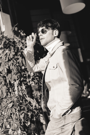 stylish man standing in sunglasses with hand in pocket, black and white photoの写真素材